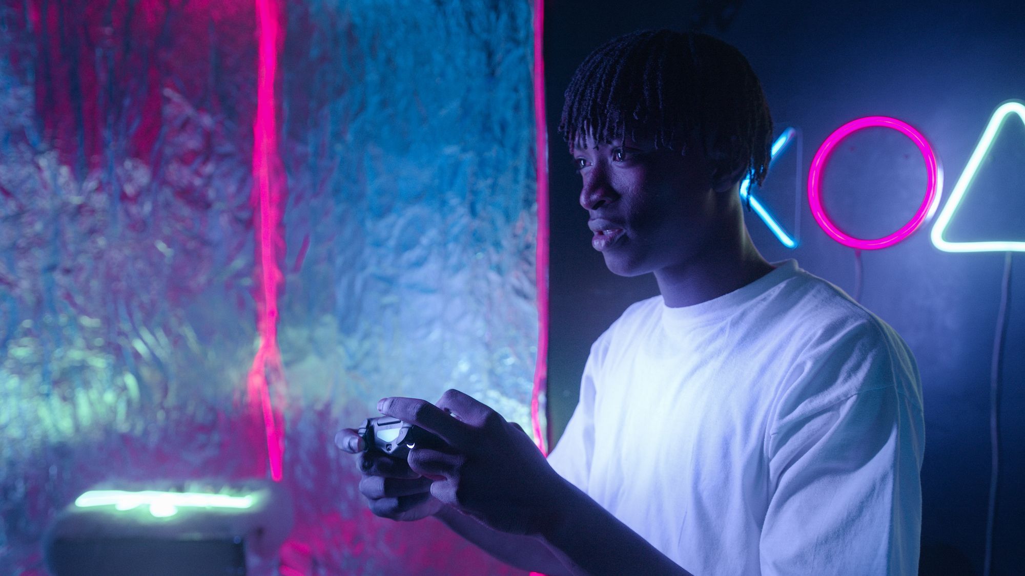 A man holding a game controller in a neon lit room