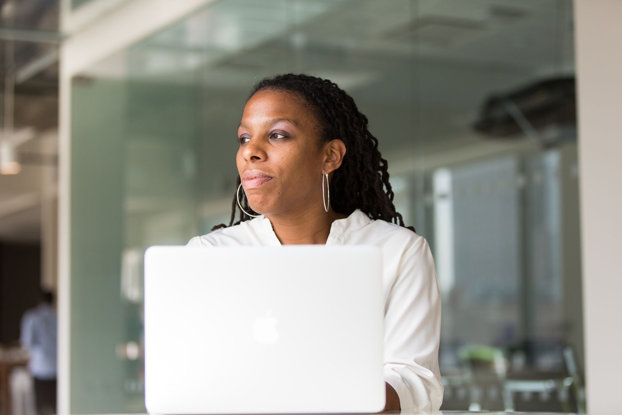 A woman sitting in front of  laptop staring to the side