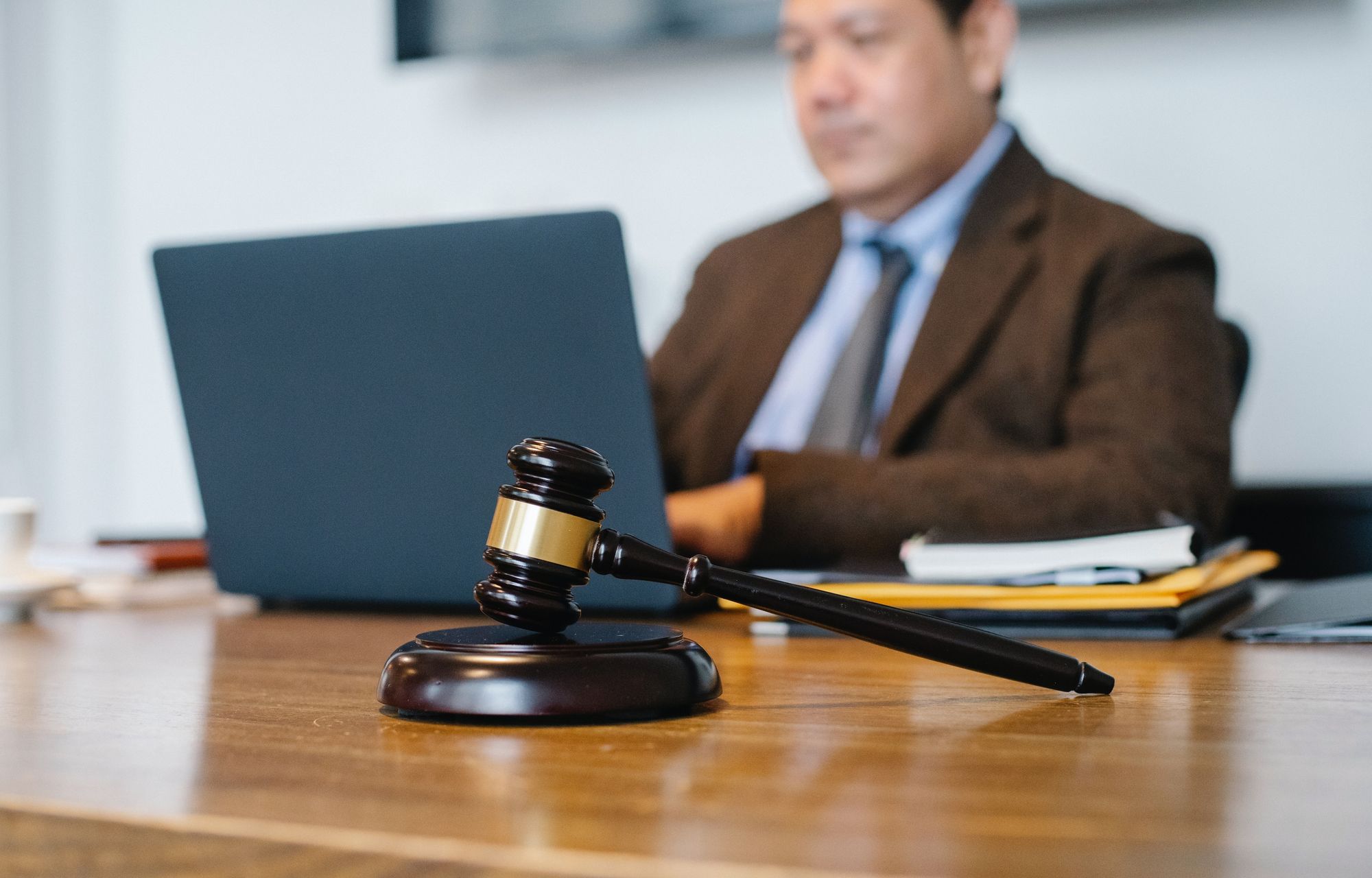 Man sitting infront of a laptop, with a gavel in front of him