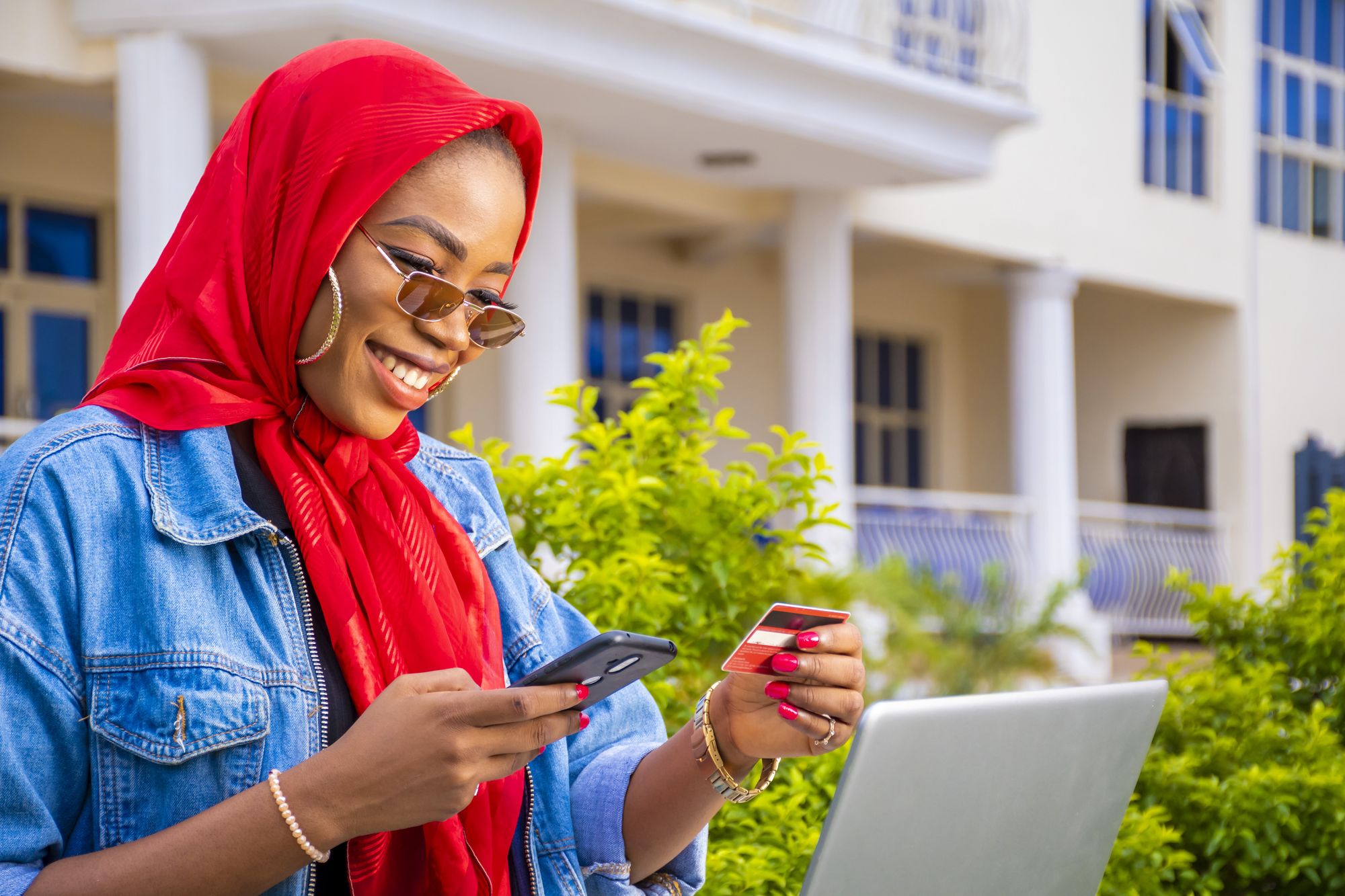 A young woman smiling and holding a mobile phone and an atm card 