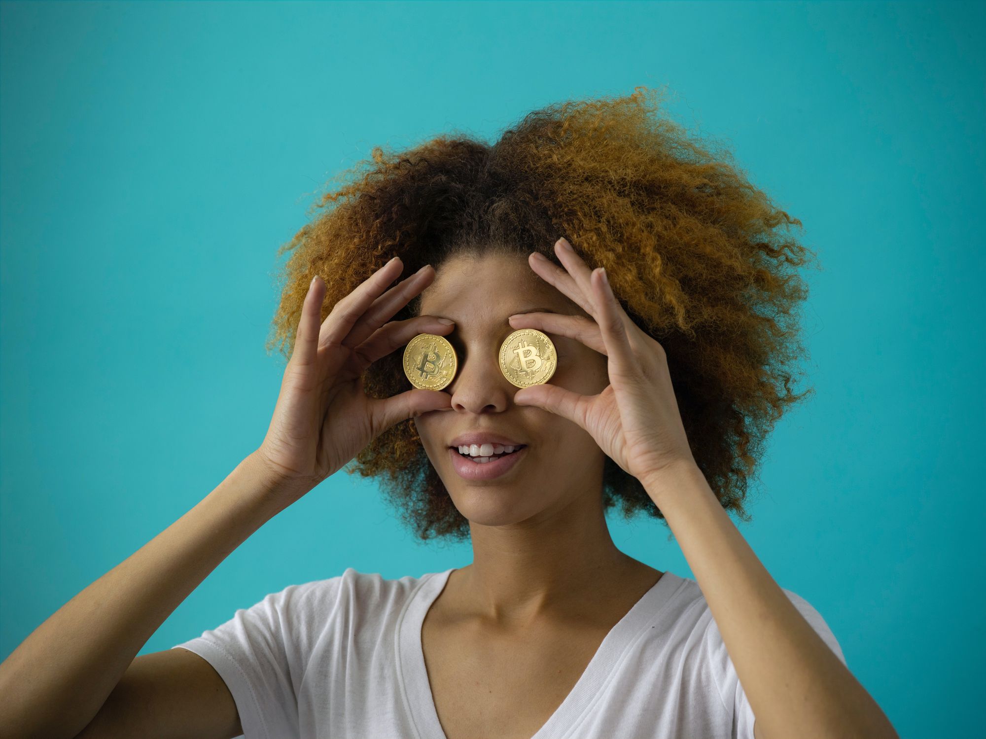 A woman holding a bitcoin over each eye