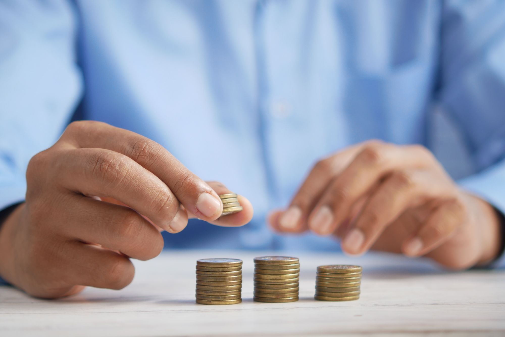 Male hands adding coins to 3 stacks of coins