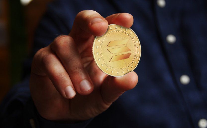a hand holding a solana coin