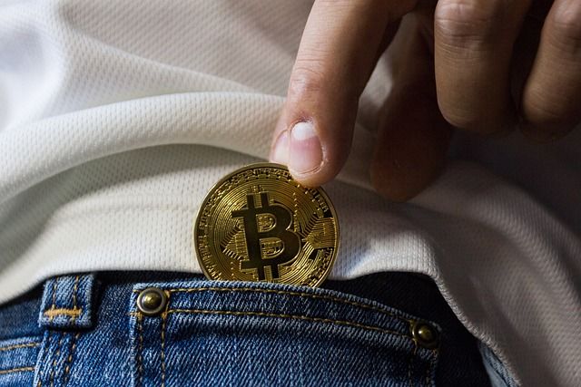 a hand putting a bitcoin in a jean pocket