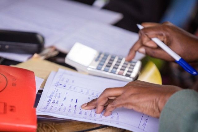 A male hand calculating their finances with a paper, pen and calculator